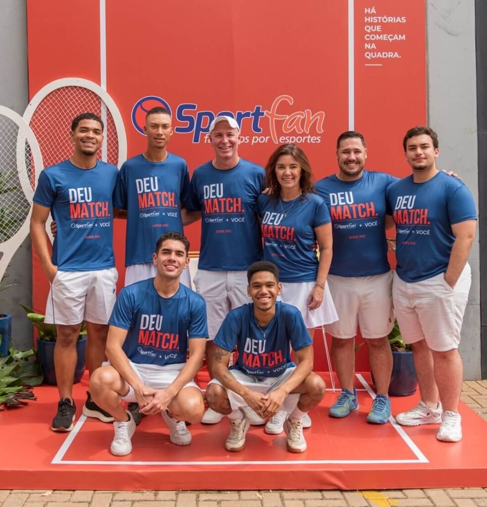 Equipe e anfitriões da Sportfan 14 anos em frente ao painel da celebração em São José do Rio Preto